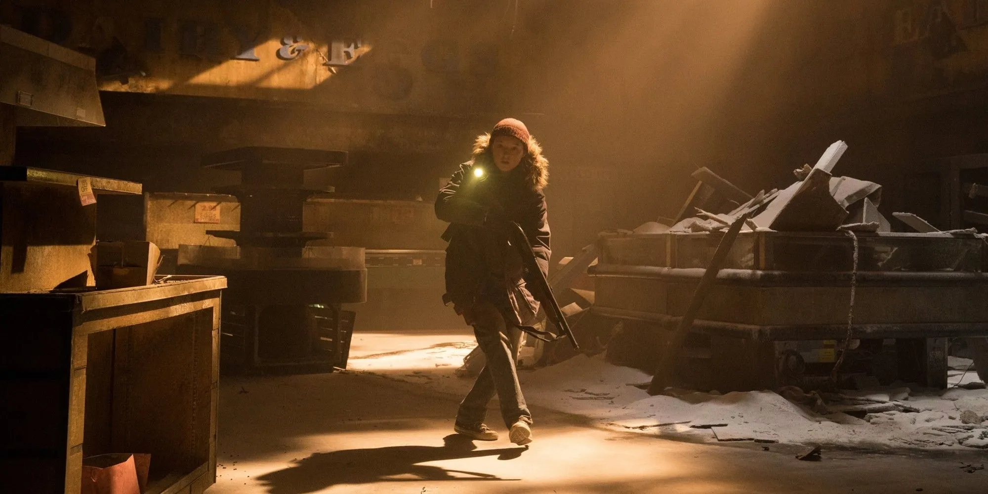 Ellie cầm súng đi trong tòa nhà đổ nát trong The Last of Us mùa 2, một nhân vật trung tâm của series.