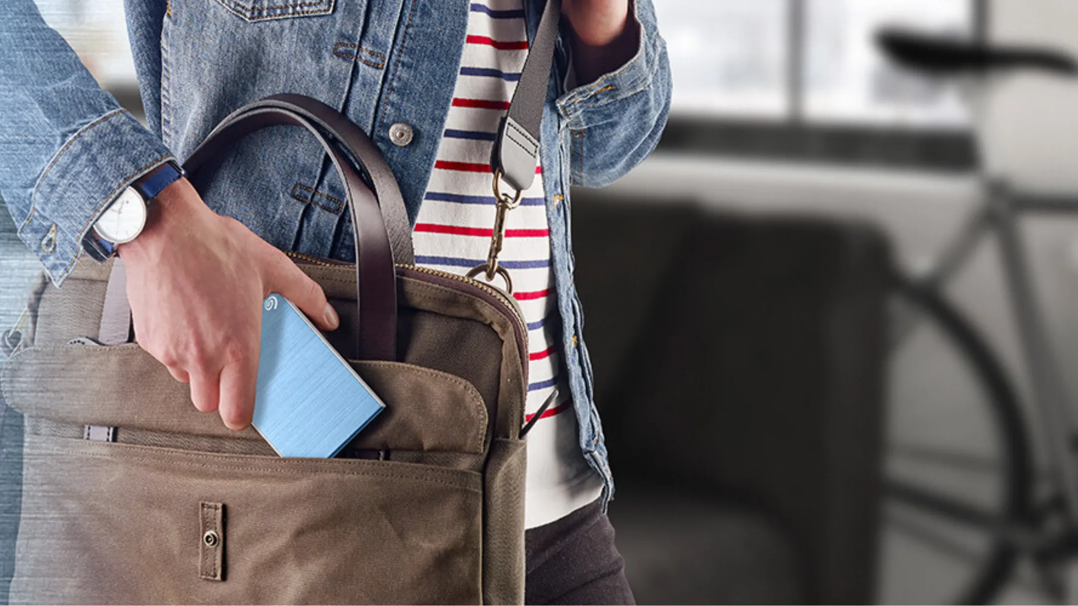 Ảnh minh họa người dùng bỏ ổ cứng Seagate Backup Plus vào balo, nêu bật tính di động và phù hợp để sao lưu dữ liệu game khi di chuyển