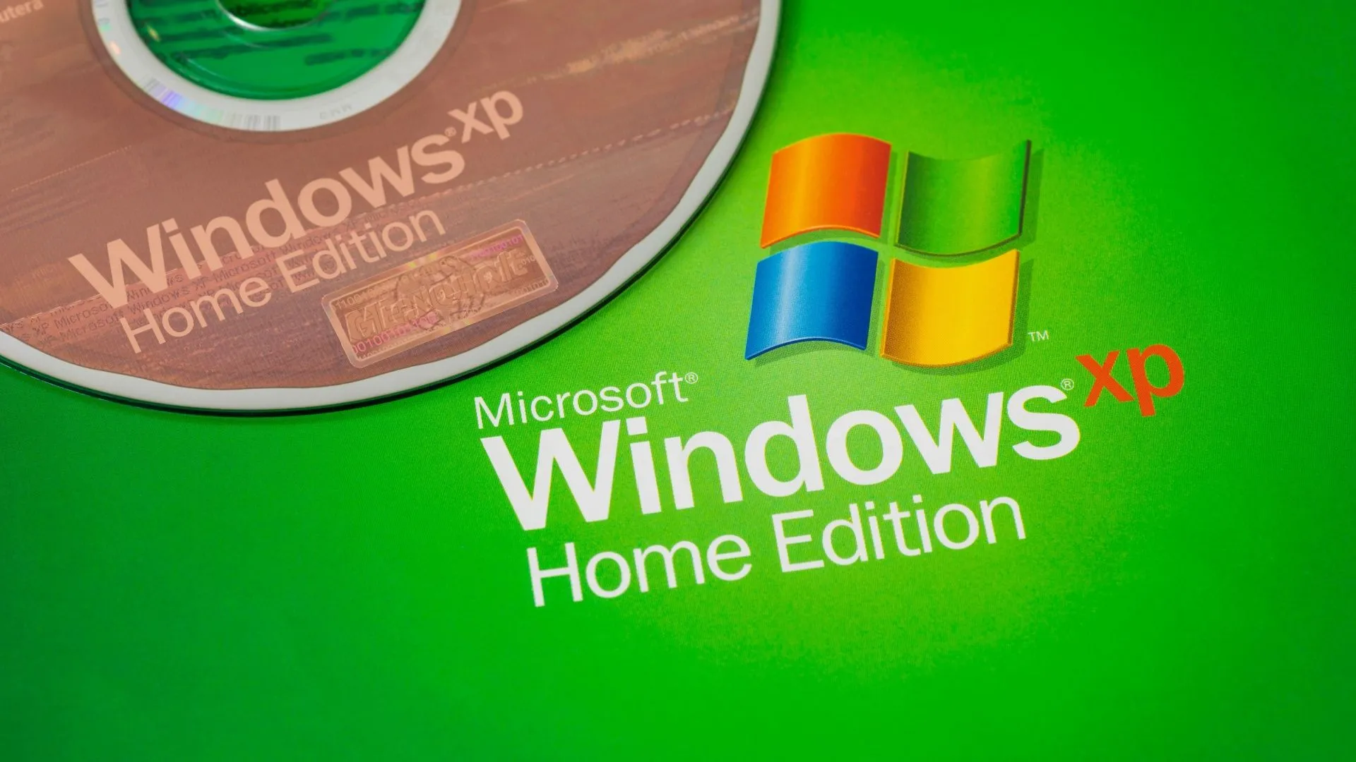 Đĩa cài Windows XP đặt cạnh logo Windows XP, tượng trưng cho quyền sở hữu phần mềm.