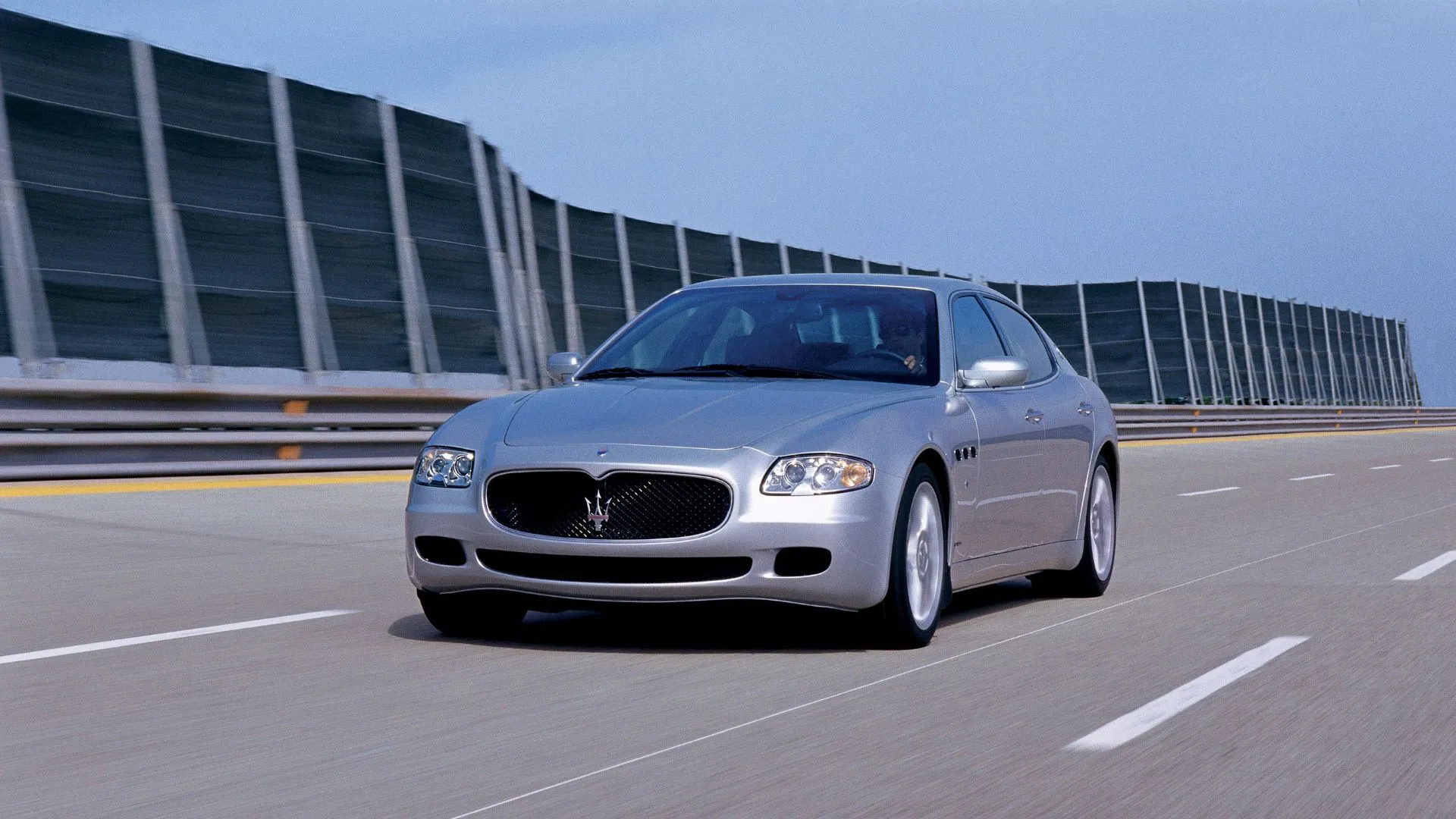 Maserati Quattroporte V (2003) góc trước 3/4 màu bạc, biểu tượng hiệu năng
