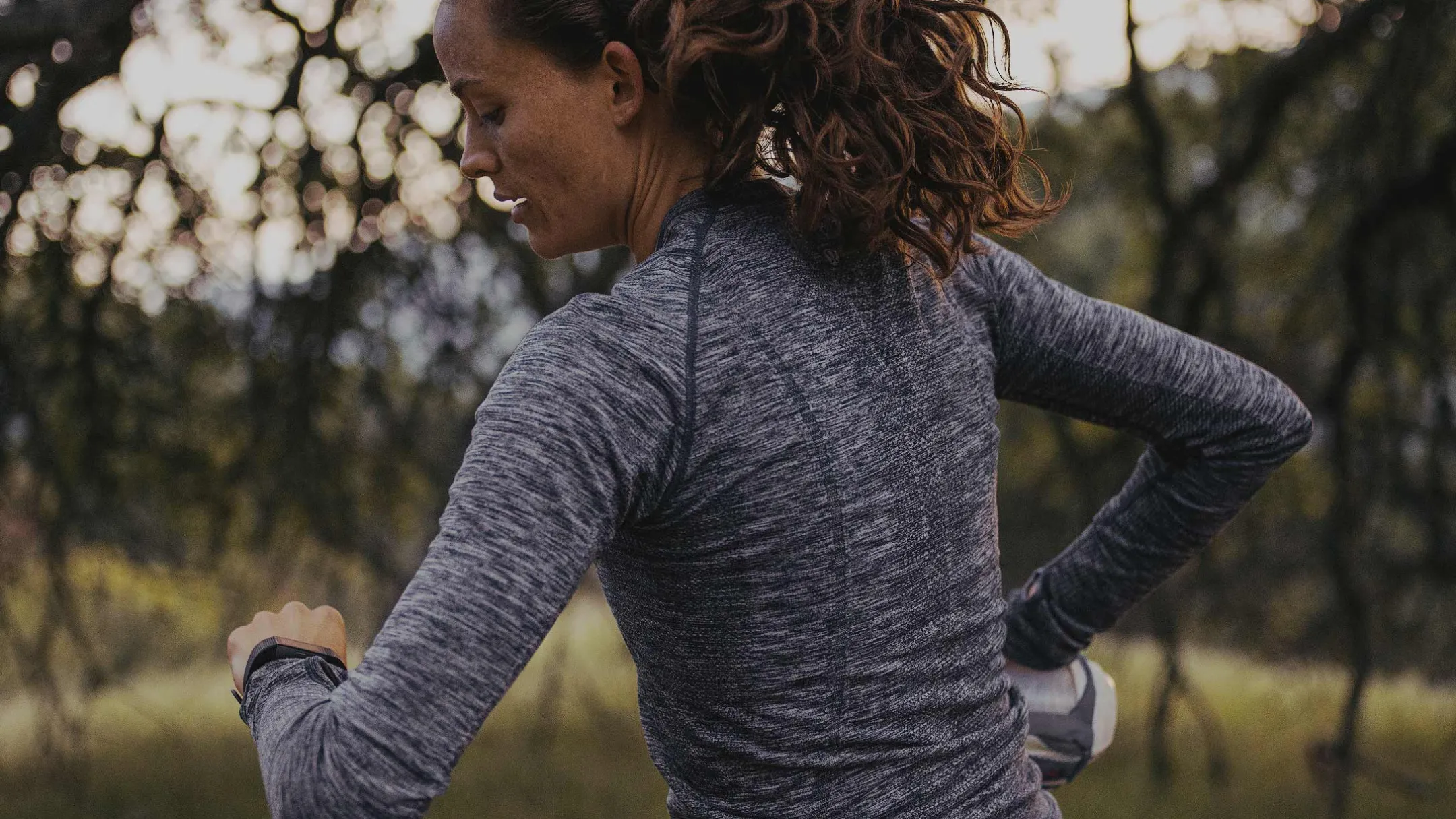 Vận động viên chạy kiểm tra đồng hồ Garmin khi ghi lại dữ liệu chạy bộ trên ứng dụng Strava